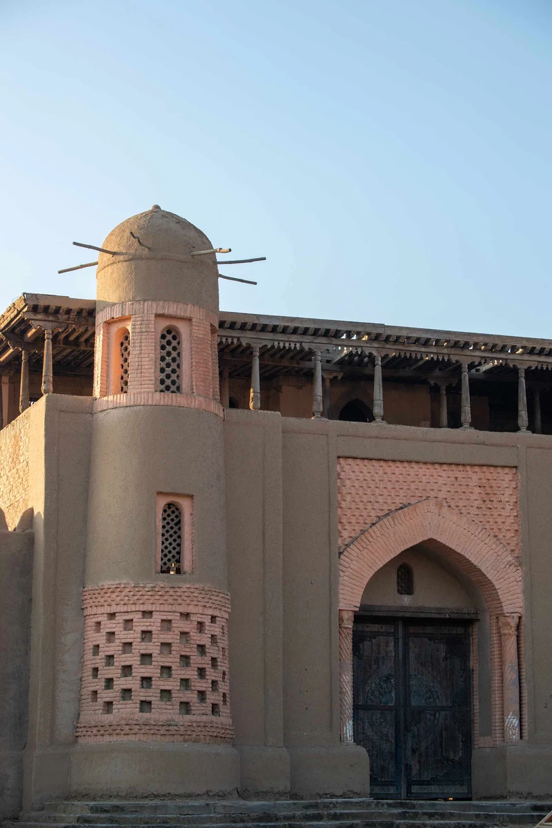 Clay building facade with a domed turret and arched wooden door at a nomad movie set
